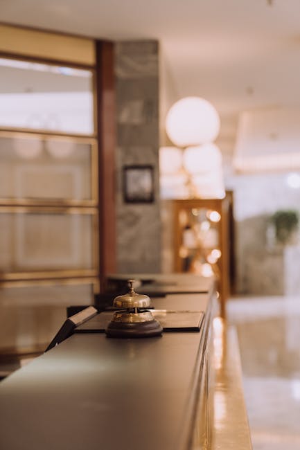 A close-up view of a hotel reception counter with a classic bell and warm lighting.
